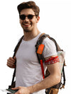 Man wearing sunglasses and a white shirt, carrying a backpack with an orange medical luggage tag attached.